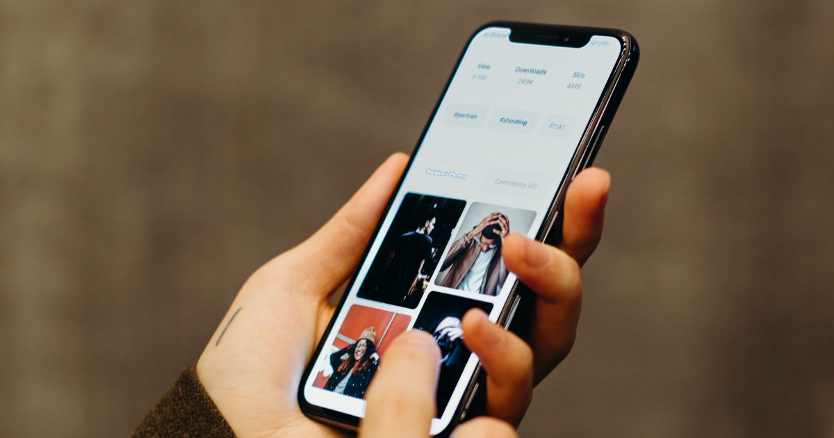 person's hand holding a phone with photos visible on the screen