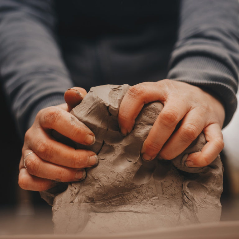 two hands shaping a lump of clay