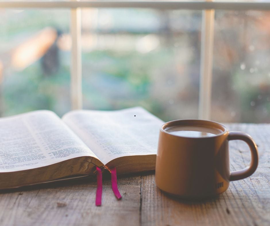 Bible open with coffee sitting near a rain splattered window